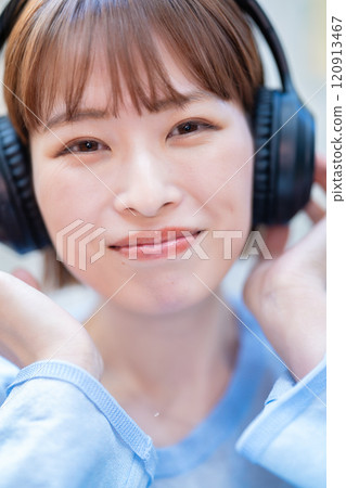 A young woman with a short bob listening to music with headphones A young woman with a short bob listening to music with headphones 120913467