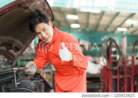 Automobile technician working in auto garage, technician holding a wrench preparing to repair broken vehicle. Professional auto or car repairman fixing a crashed car. 120913623