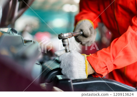 Automobile technician working in auto garage, technician holding a wrench preparing to repair broken vehicle. Professional auto or car repairman fixing a crashed car. 120913624