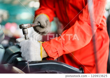 Automobile technician working in auto garage, technician holding a wrench preparing to repair broken vehicle. Professional auto or car repairman fixing a crashed car. Automobile technician working in auto garage, technician holding a wrench preparing to repair broken vehicle. Professional auto or car repairman fixing a crashed car. 120913625