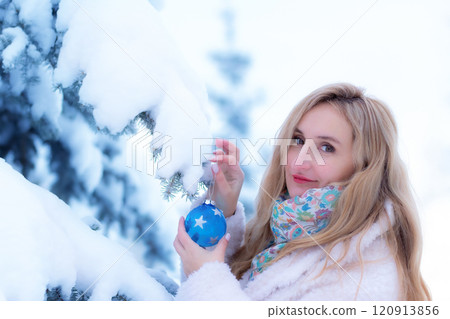 Woman in white coat with a Christmas decoration in winter forest. 120913856