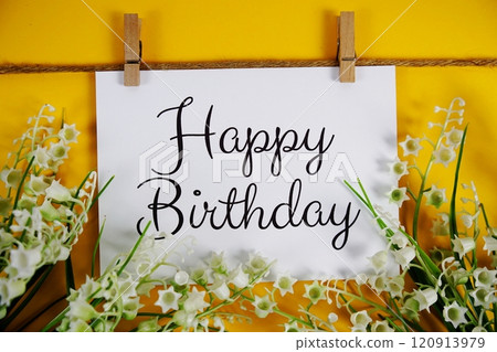 Happy Birthday text on paper card with flower blooming decoration on yellow background Happy Birthday text on paper card with flower blooming decoration on yellow background 120913979