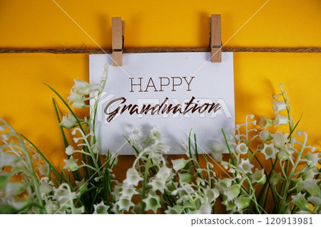 Happy Graduation text on paper card with flower blooming decoration on yellow background Happy Graduation text on paper card with flower blooming decoration on yellow background 120913981