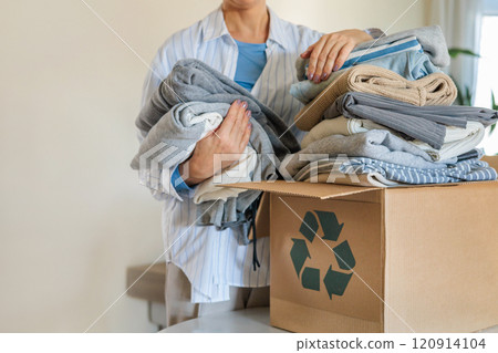 Pile of clothes in cardboard box donating for recycling reusing at living room with houseplant Pile of clothes in cardboard box donating for recycling reusing at living room with houseplant 120914104