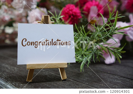 Congratulations text write on paper card with wooden easel and flowers decoration on wooden background Congratulations text write on paper card with wooden easel and flowers decoration on wooden background 120914301