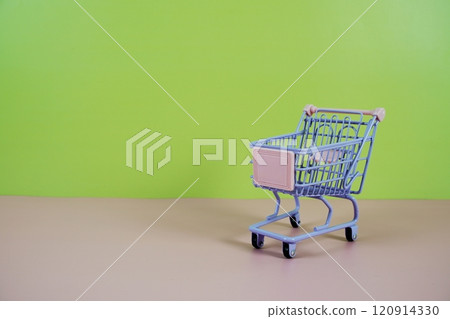Mini Trolley shopping cart with space for text on pink and green background 120914330
