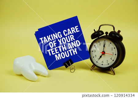 Taking Care of Your Teeth and Mouth text on paper card with stethoscope, alarm clock and white tooth model on yellow background Taking Care of Your Teeth and Mouth text on paper card with stethoscope, alarm clock and white tooth model on yellow background 120914334