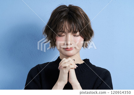 一個留著短髮、看起來在祈禱的年輕女子 120914350