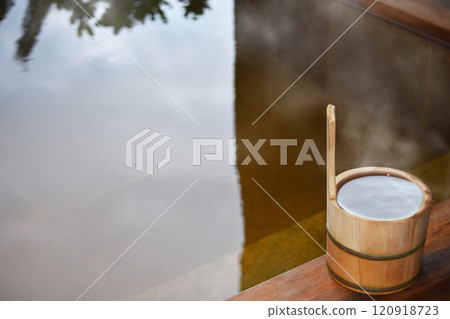 A cypress bucket placed in an open-air cypress bath with steam rising from it A cypress bucket placed in an open-air cypress bath with steam rising from it 120918723