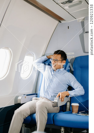 Photo of a frustrated man sitting on an airplane with her head in her hands. Asian Businessman sitting in airplane working Photo of a frustrated man sitting on an airplane with her head in her hands. Asian Businessman sitting in airplane working 120921338