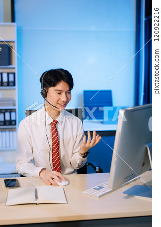 Serious call center operator in wireless headset talking with customer, Asian man with microphone consulting client on phone in customer support service 120922216