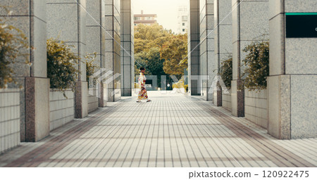 Woman, kimono and walking in city, buildings and travel with profile on urban sidewalk in summer at park. Person, outdoor and traditional fashion with style, clothes and heritage on commute in Japan 120922475