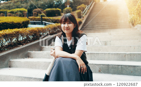 Girl, college student and portrait on stairs, outdoor and happy on break at campus in sunshine. Woman, person and smile on steps in garden with pride, confidence and education at university in Japan 120922687