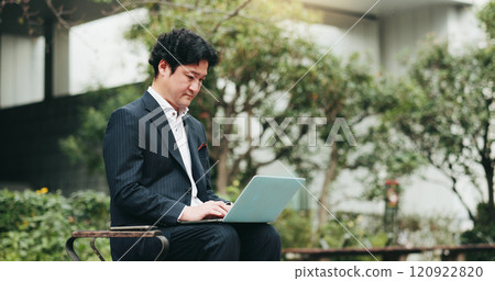 Laptop, business man and typing at park for remote work, info or environmental consultant writing email on bench. Japanese worker, online or computer in city for sustainable project, review or update Laptop, business man and typing at park for remote work, info or environmental consultant writing email on bench. Japanese worker, online or computer in city for sustainable project, review or update 120922820