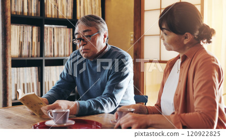 Love, reading and retirement with senior couple in home together for hobby or wellness. Book, leisure or literature with old Japanese man and woman in apartment to relax for morning or weekend 120922825