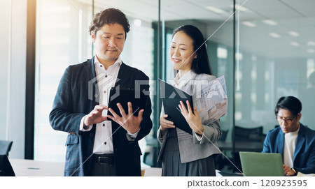 Business, tablet or Asian people in office for documents, planning investment or revenue. Woman, meeting or sales review with man, feedback or teamwork for online project, agenda and budget in Japan 120923595
