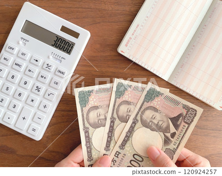 拿著30,000日元、計算器和存摺的婦女的手 120924257