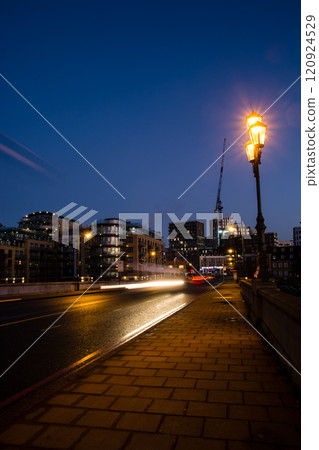 Street lights and car lights streaking past on the cobbled and paved roads of Kew Bridge at sunrise 120924529