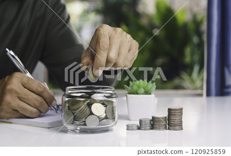 Hand with money coins in clear glass, Business investment growth concept, saving concept, Hand putting coin in clear jar. Hand with money coins in clear glass, Business investment growth concept, saving concept, Hand putting coin in clear jar. 120925859
