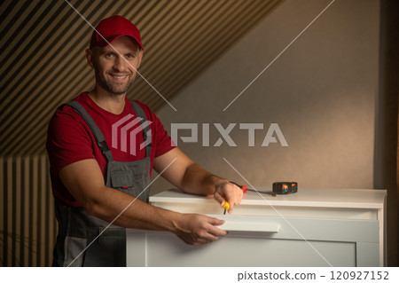 Man works on furniture assembly in a bright room, showcasing DIY skills and tools 120927152