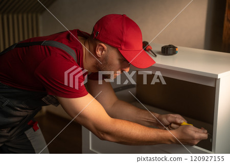 Interior carpenter measures and assembles furniture in a bright home environment 120927155