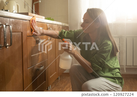 Cleaning kitchen cabinets with an effective spray in a bright home environment Cleaning kitchen cabinets with an effective spray in a bright home environment 120927224