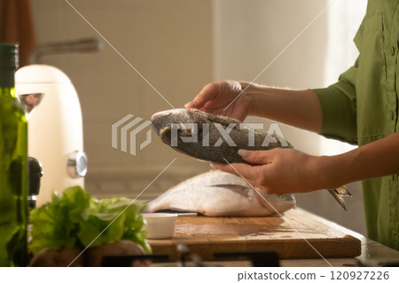 Preparing dorado fish on a baking sheet in a cozy kitchen for a delicious meal 120927226