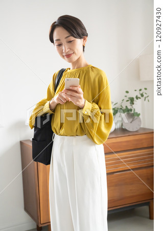 Middle-aged woman looking at her smartphone indoors 120927430