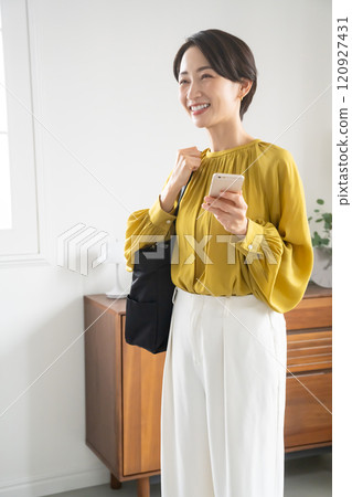 Middle-aged woman looking at her smartphone indoors 120927431