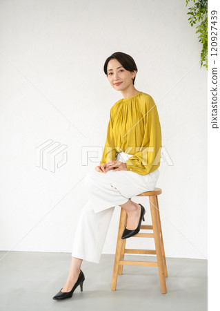 Young woman posing while sitting on a chair in a room Young woman posing while sitting on a chair in a room 120927439