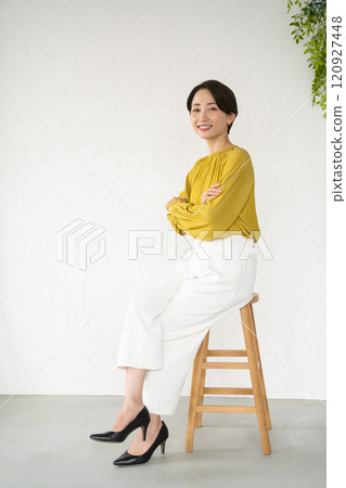 坐在房間椅上擺姿勢的年輕女子 120927448