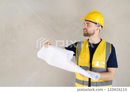 Portrait of smart and good looking caucasian white male foreman or construction contractor reviewing the building layout on blueprint close up. Construction contractor - inspecting blueprint on paper. Portrait of smart and good looking caucasian white male foreman or construction contractor reviewing the building layout on blueprint close up. Construction contractor - inspecting blueprint on paper. 120928210