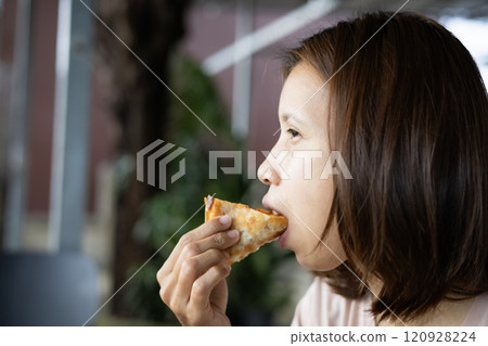 Face of woman biting slice of pizza outdoors. Face of woman biting slice of pizza outdoors. 120928224