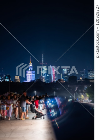 night over skyline of modern city with skyscrapers and downtown district, crowd of people walking, tourist travel destination, rush hour in Warsaw, capital of Poland 120928227