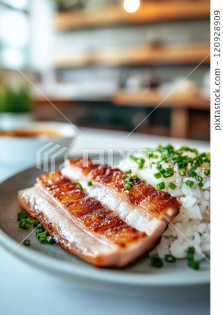 Grilled pork belly slices served with steamed rice and garnished with fresh green onions on plate in cozy dining atmosphere, emphasizing delicious homemade cuisine. Traditional Chinese dish Grilled pork belly slices served with steamed rice and garnished with fresh green onions on plate in cozy dining atmosphere, emphasizing delicious homemade cuisine. Traditional Chinese dish 120928909