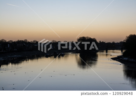 The River Thames reflecting the pre-dawn glow and a streetscape lined with winter trees and street lamps in Kew Bridge, a suburb of London The River Thames reflecting the pre-dawn glow and a streetscape lined with winter trees and street lamps in Kew Bridge, a suburb of London 120929048