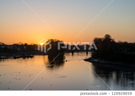 The River Thames reflecting the pre-dawn glow and a streetscape lined with winter trees and street lamps in Kew Bridge, a suburb of London The River Thames reflecting the pre-dawn glow and a streetscape lined with winter trees and street lamps in Kew Bridge, a suburb of London 120929059