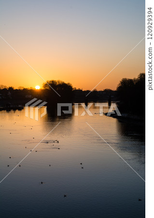 The River Thames reflecting the pre-dawn glow and a streetscape lined with winter trees and street lamps in Kew Bridge, a suburb of London The River Thames reflecting the pre-dawn glow and a streetscape lined with winter trees and street lamps in Kew Bridge, a suburb of London 120929394