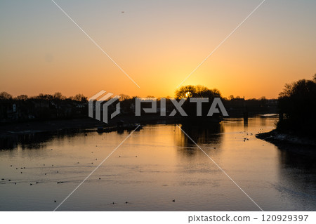 倫敦郊區的邱橋,泰晤士河反射著黎明前的日出,城市景觀排列著冬季樹枝和路燈 倫敦郊區的邱橋,泰晤士河反射著黎明前的日出,城市景觀排列著冬季樹枝和路燈 120929397