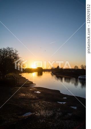 The River Thames reflecting the pre-dawn glow and a streetscape lined with winter trees and street lamps in Kew Bridge, a suburb of London The River Thames reflecting the pre-dawn glow and a streetscape lined with winter trees and street lamps in Kew Bridge, a suburb of London 120929552