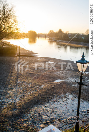 The River Thames illuminated by the rising sun and the riverbed exposed by the low tide, Kew Bridge, on the outskirts of London 120929648