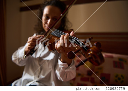 Close-up of a person skillfully playing the violin indoors with focus 120929759