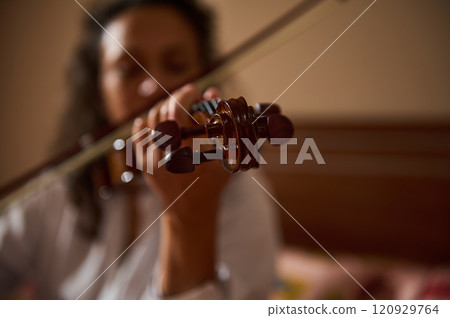 Close-up of a violinist playing music in warm cozy setting Close-up of a violinist playing music in warm cozy setting 120929764