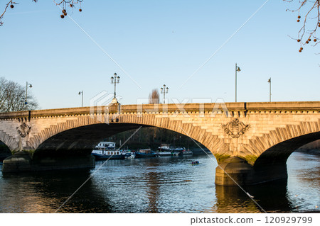 Kew Bridge, a historic stone arch structure spanning the River Thames bathed in the orange sunlight of early morning Kew Bridge, a historic stone arch structure spanning the River Thames bathed in the orange sunlight of early morning 120929799