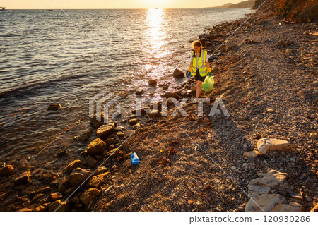 Earth day and environmental conservation. Top view of young volunteer walking at beach holding plastic bag full of trash. Concept of ocean's pollution and protection of ecology 120930286