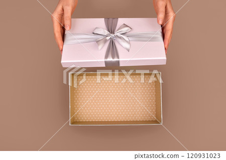 Woman opening empty pink gift box silver ribbon bow Mocha Mousse background 120931023