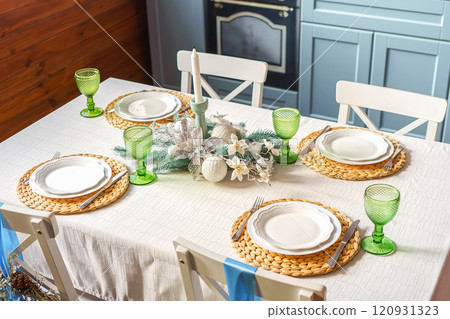 Stylish dining table set for holiday dinner in modern kitchen with blue accents background 120931323
