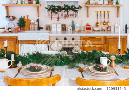 Elegant Christmas holiday table setting with greenery and simple decor on cozy kitchen background 120931343