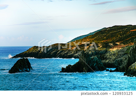 A view of a rocky coastline with a blue ocean. The water is a deep blue in color. The sky is clear and blue. A view of a rocky coastline with a blue ocean. The water is a deep blue in color. The sky is clear and blue. 120933125
