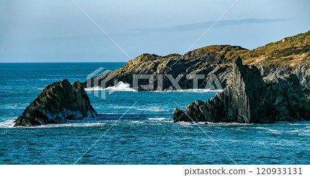 A view of a rocky coastline with a blue ocean. The water is a deep blue in color. A view of a rocky coastline with a blue ocean. The water is a deep blue in color. 120933131